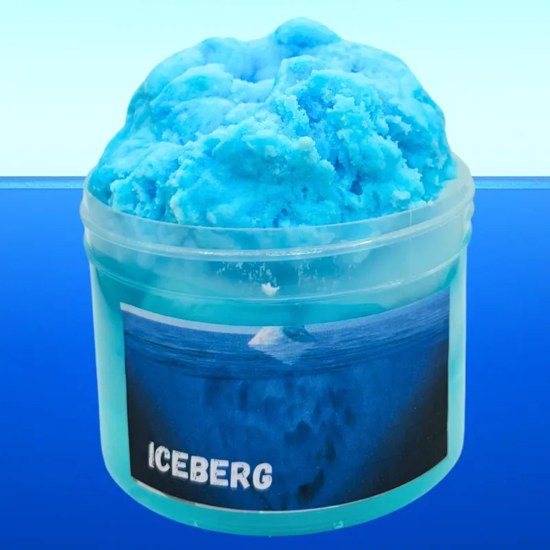 Iceberg jar with fluffy blue snow slime over blue clear slime, in front of the ocean
